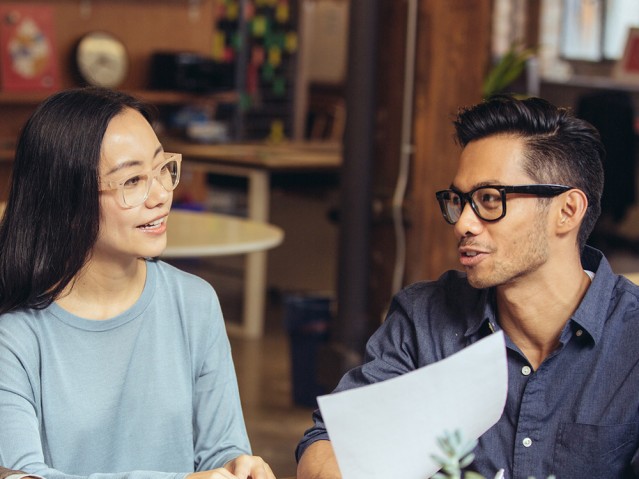 A lady and a man looking over paperwork at a desk