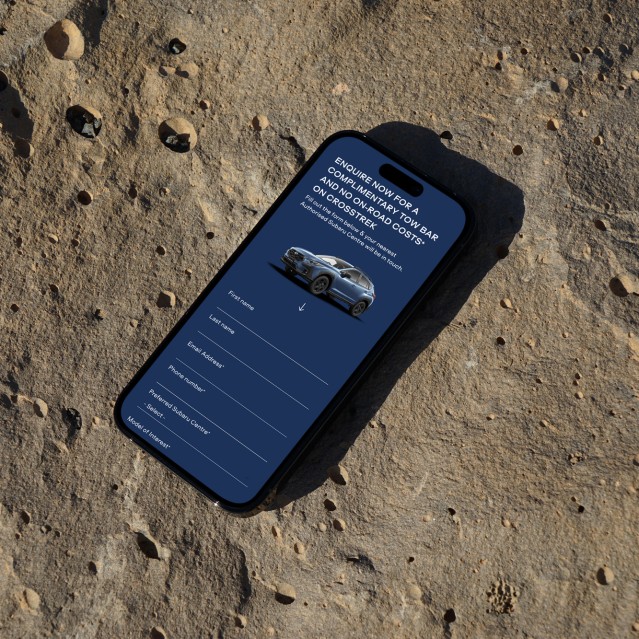 Subaru website on a phone sitting on a rock